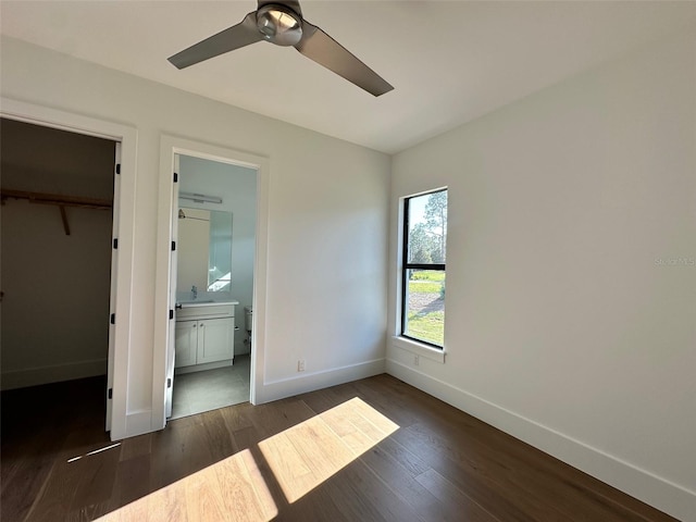 unfurnished bedroom featuring connected bathroom, sink, ceiling fan, dark wood-type flooring, and a closet