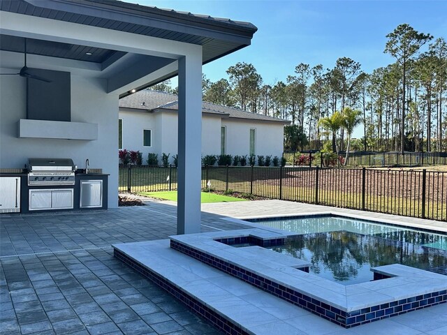 view of swimming pool featuring an outdoor kitchen, a grill, sink, ceiling fan, and a patio area