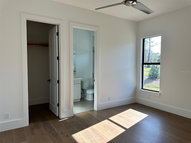 unfurnished bedroom featuring dark wood-type flooring, a walk in closet, a closet, and ensuite bathroom