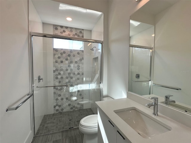 bathroom with vanity, a shower with shower door, and toilet