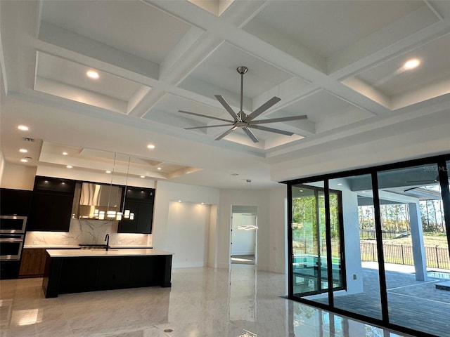 kitchen featuring appliances with stainless steel finishes, coffered ceiling, a kitchen island with sink, and decorative backsplash