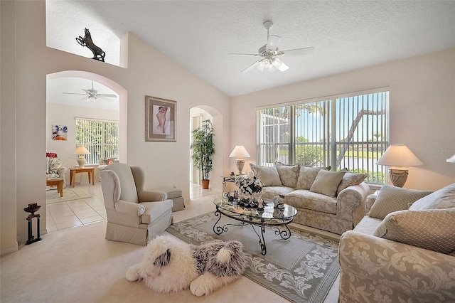 living room with a textured ceiling, ceiling fan, light tile patterned floors, and lofted ceiling