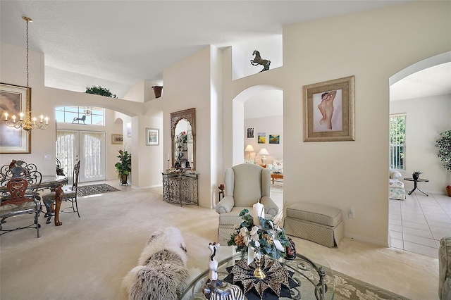 carpeted living room featuring a chandelier, french doors, a healthy amount of sunlight, and a high ceiling