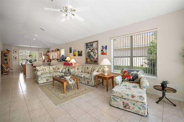 living room with ceiling fan, light tile patterned floors, a textured ceiling, and vaulted ceiling