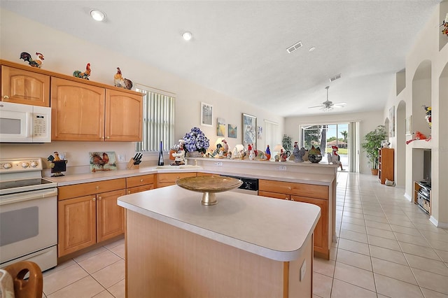 kitchen with ceiling fan, light tile patterned flooring, kitchen peninsula, white appliances, and a kitchen island