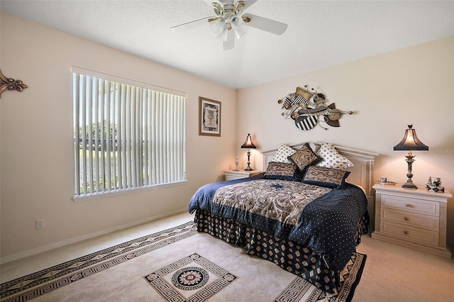 bedroom with ceiling fan, light colored carpet, a textured ceiling, and multiple windows