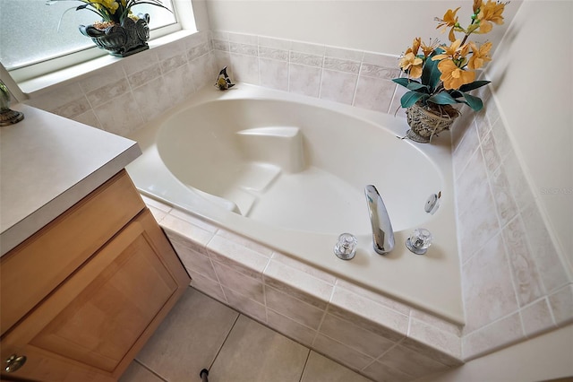 bathroom with tile patterned flooring, vanity, and a relaxing tiled tub