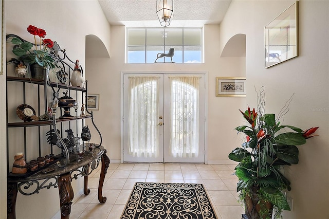 tiled foyer with french doors, a high ceiling, and a textured ceiling