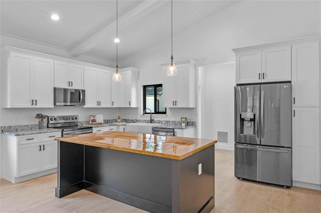 kitchen with white cabinets, beamed ceiling, appliances with stainless steel finishes, and light wood-type flooring