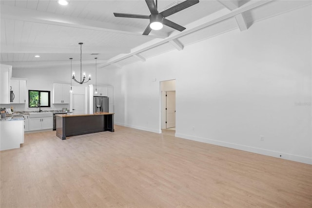 unfurnished living room featuring beam ceiling, light wood-type flooring, and ceiling fan with notable chandelier