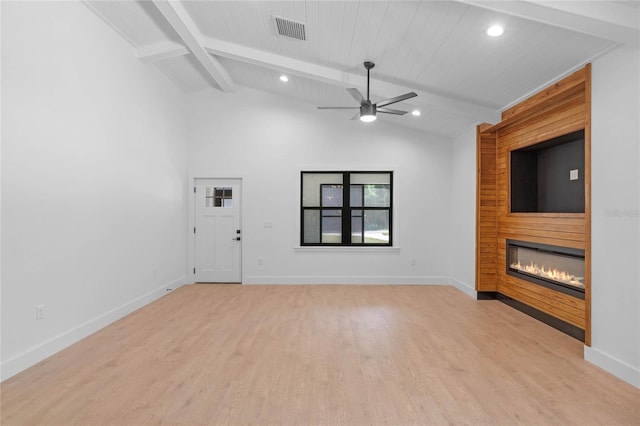 spare room featuring vaulted ceiling with beams, a fireplace, light wood-type flooring, and ceiling fan