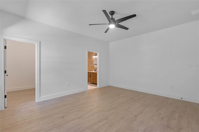 unfurnished bedroom with ceiling fan, a walk in closet, light wood-type flooring, and ensuite bath