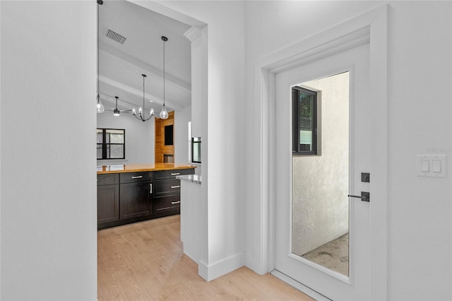 corridor with light hardwood / wood-style floors, a chandelier, and beam ceiling