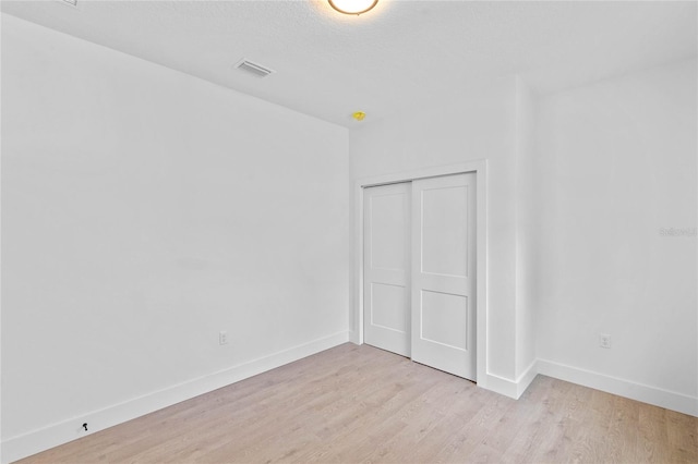 unfurnished bedroom with a closet and light wood-type flooring