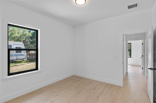 empty room featuring a healthy amount of sunlight and light hardwood / wood-style floors