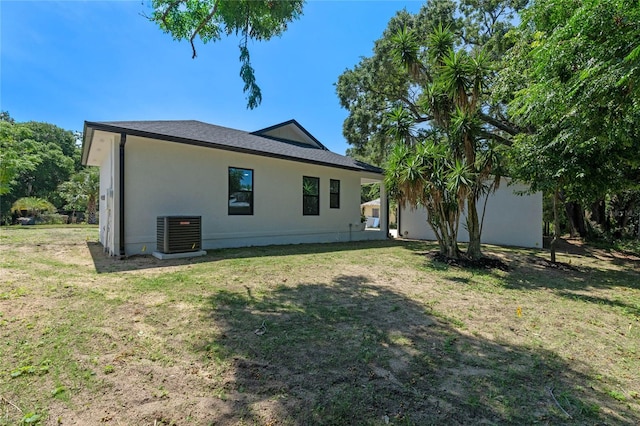 back of property featuring central air condition unit and a lawn