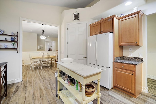 kitchen featuring hanging light fixtures, white fridge, and light wood-type flooring