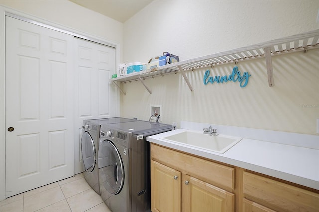 laundry room with cabinets, light tile patterned flooring, separate washer and dryer, and sink