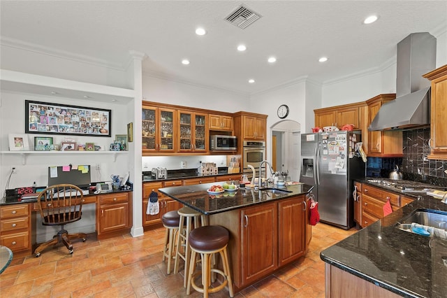 kitchen featuring sink, light tile patterned floors, stainless steel appliances, a center island with sink, and wall chimney range hood