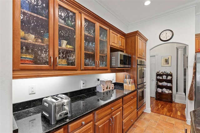 kitchen with light hardwood / wood-style floors, appliances with stainless steel finishes, crown molding, and dark stone countertops