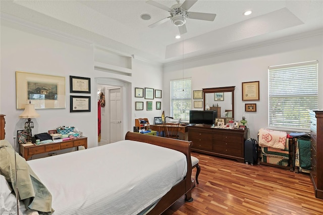 bedroom featuring hardwood / wood-style floors, ceiling fan, and a tray ceiling