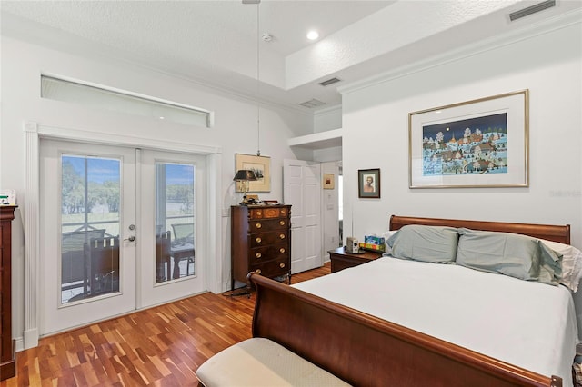 bedroom featuring a raised ceiling, hardwood / wood-style floors, access to exterior, and french doors