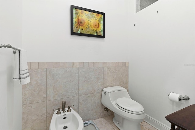 bathroom with tile walls, toilet, a bidet, and tile patterned floors