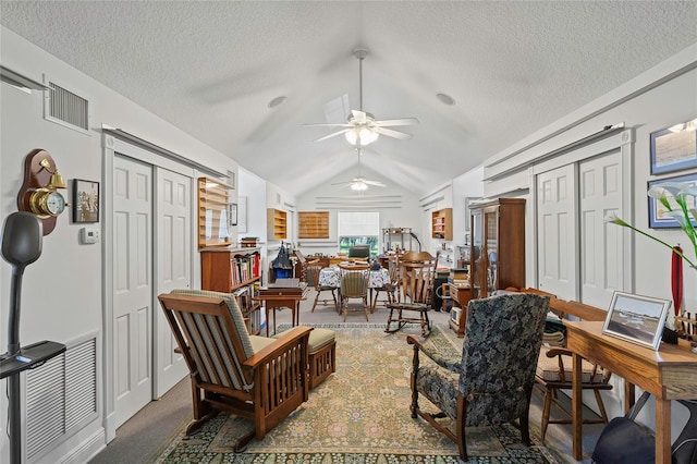 carpeted living room with ceiling fan, a textured ceiling, and lofted ceiling