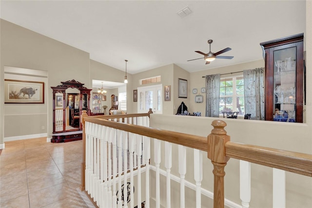 hall with tile patterned flooring, vaulted ceiling, and an inviting chandelier