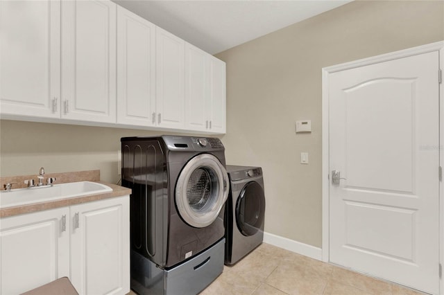 laundry area featuring light tile patterned floors, cabinets, washer and dryer, and sink