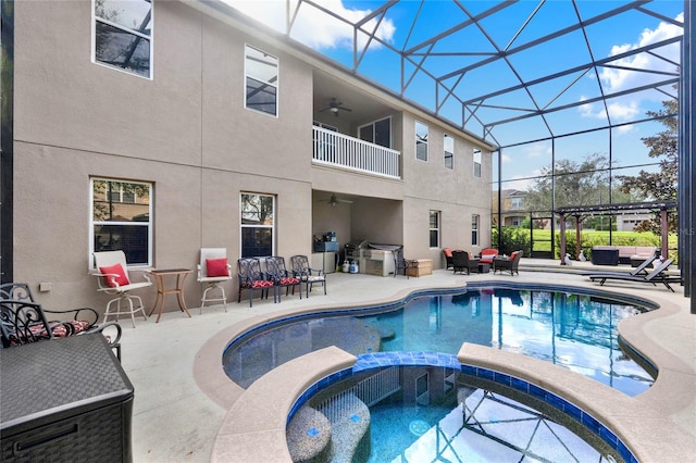 view of swimming pool featuring glass enclosure, an in ground hot tub, a patio area, ceiling fan, and a pergola