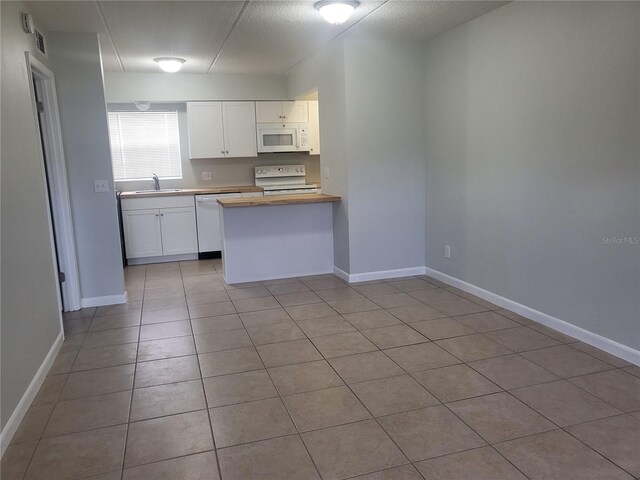 kitchen with sink, white cabinetry, white appliances, and light tile floors