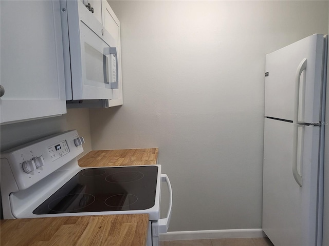 kitchen with white cabinets, tile flooring, and white appliances