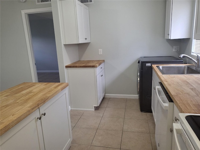 kitchen with dishwasher, butcher block counters, light tile flooring, range, and white cabinetry