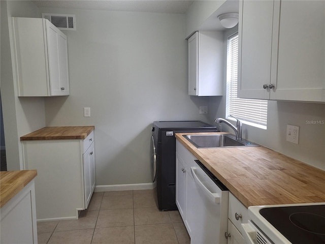 kitchen featuring white cabinetry, stainless steel dishwasher, wooden counters, sink, and light tile floors