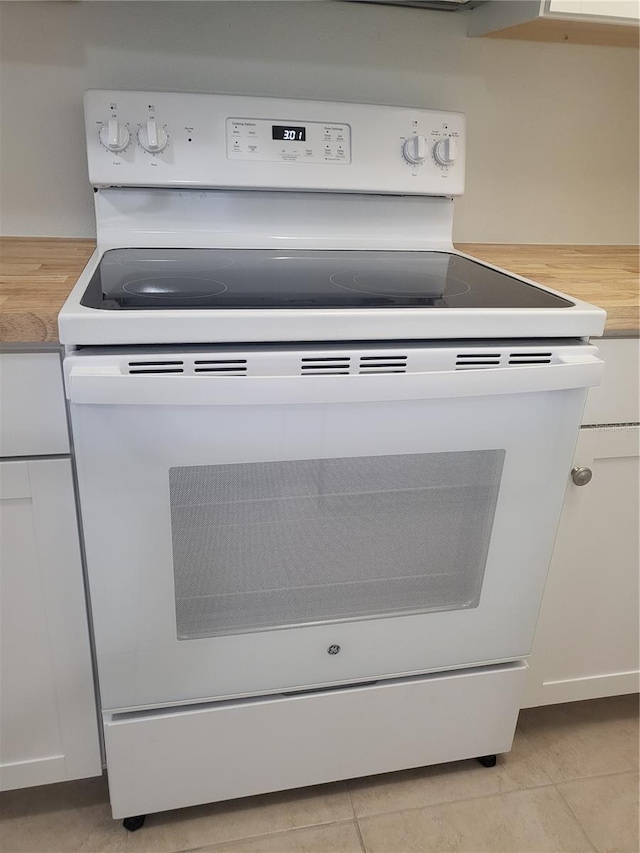 details with wooden counters, white cabinetry, electric range, and light tile floors