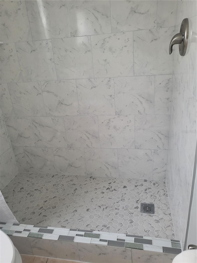 bathroom with a tile shower and toilet