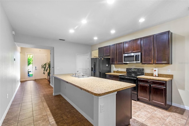 kitchen featuring sink, a kitchen bar, a kitchen island with sink, light tile patterned floors, and black appliances