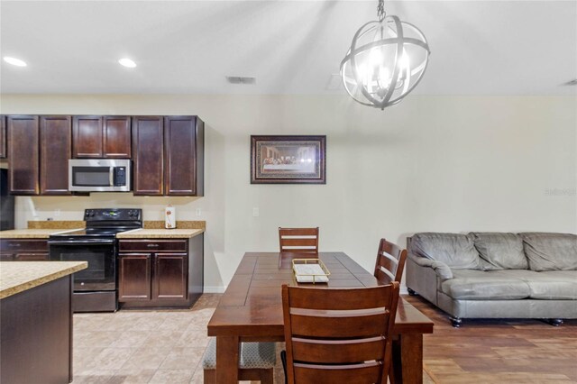 kitchen with a chandelier, dark brown cabinets, electric range, and hanging light fixtures