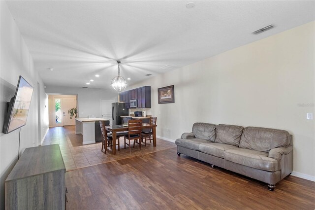 living room with dark hardwood / wood-style floors and an inviting chandelier