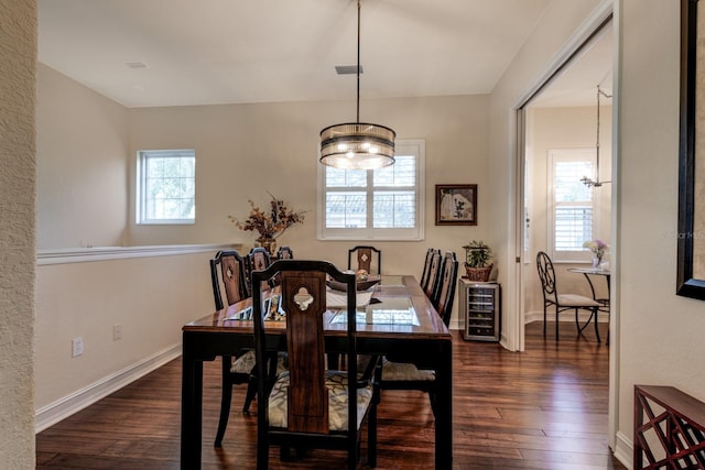 dining space featuring a notable chandelier, dark wood-type flooring, and wine cooler