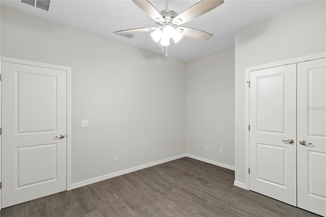 unfurnished bedroom with dark hardwood / wood-style flooring, a closet, and ceiling fan