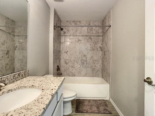 full bathroom featuring vanity, tiled shower / bath combo, and toilet