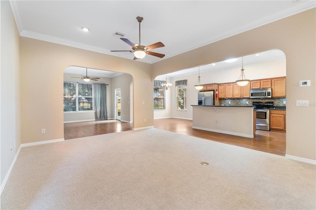 unfurnished living room with ceiling fan with notable chandelier, crown molding, and light carpet