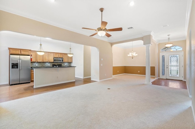 unfurnished living room with ceiling fan with notable chandelier, light carpet, decorative columns, and ornamental molding