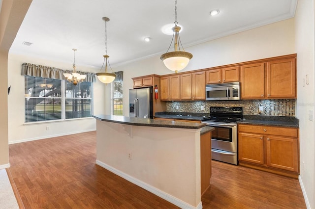 kitchen with stainless steel appliances, an inviting chandelier, crown molding, and a kitchen island