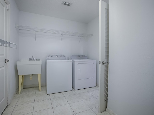 laundry room with washing machine and clothes dryer and light tile patterned flooring