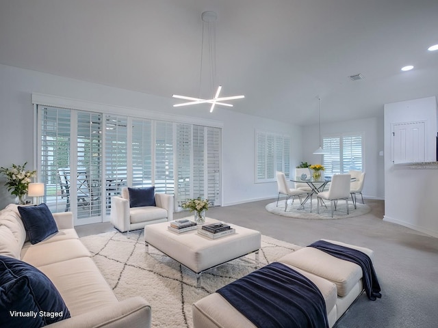 carpeted living room with a chandelier