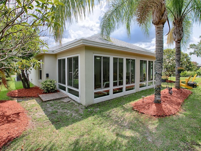 back of property with a yard and a sunroom