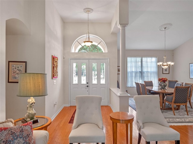 foyer entrance with an inviting chandelier, decorative columns, and light hardwood / wood-style flooring